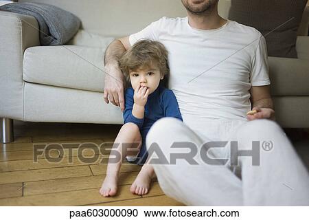 Toddler boy sitting by father with fingers in mouth View Large Photo Image Stock Image - Toddler boy sitting by father with fingers in mouth. Fotosearch