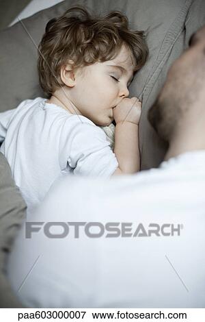 Toddler boy sleeping beside father, cropped View Large Photo Image Stock Photo - Toddler boy sleeping beside father, cropped. Fotosearch