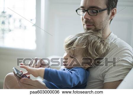 Toddler boy touching father's cell phone curiously View Large Photo Image Stock Photograph - Toddler boy touching father's cell phone curiously. Fotosearch