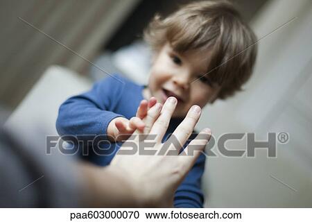 Stock Image - Toddler boy touching parent's hand. Fotosearch