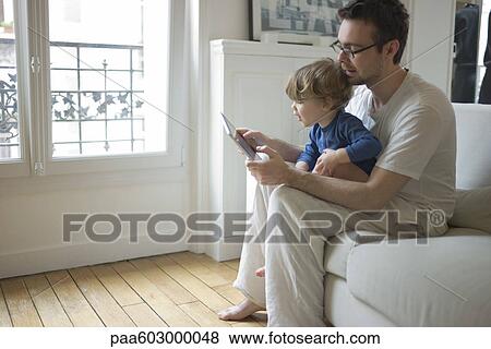 Toddler boy watching father using digital tablet View Large Photo Image Stock Photo - Toddler boy watching father using digital tablet. Fotosearch