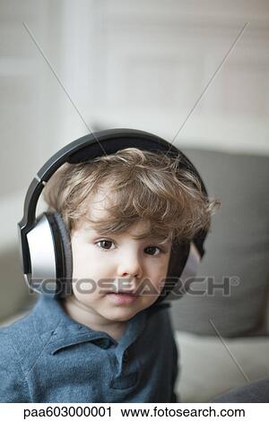 Stock Image - Toddler boy wearing headphones, portrait. Fotosearch