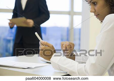 Businesswoman looking at cell phone View Large Photo Image Stock Photo - Businesswoman looking at cell phone. Fotosearch