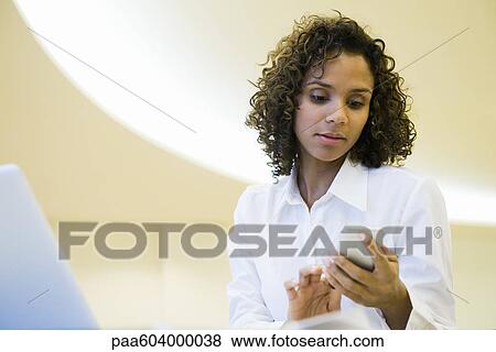 Stock Photo - Businesswoman text messaging with cell phone. Fotosearch