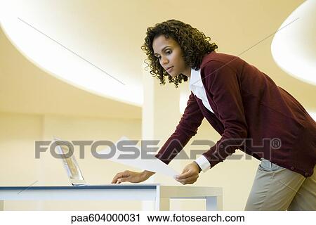 Businesswoman using laptop computer and looking at document View Large Photo Image Stock Image - Businesswoman using laptop computer and looking at document. Fotosearch