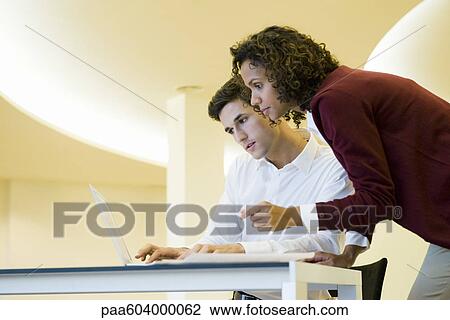 Stock Image - Colleagues using laptop computer together. Fotosearch