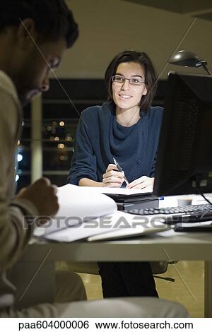 Colleagues working on project together in office at night View Large Photo Image Stock Photograph - Colleagues working on project together in office at night. Fotosearch