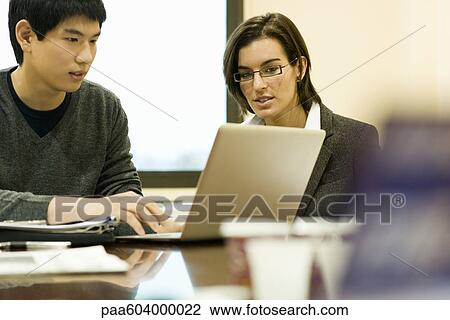 Stock Image - Colleagues working together on laptop computer. Fotosearch