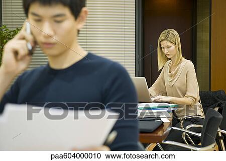 Female executive working on laptop computer, colleague in foreground View Large Photo Image Stock Image - Female executive working on laptop computer, colleague in foreground. Fotosearch