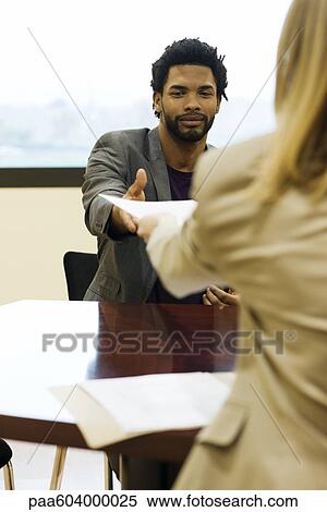 Stock Photography - Man handing prospective employer his resume during job interview. Fotosearch