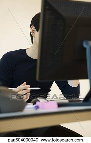 Office worker sitting at desk with computer View Large Photo Image Stock Image - Office worker sitting at desk with computer. Fotosearch