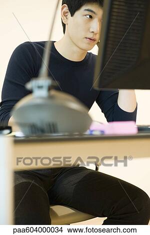 Young man working at desk View Large Photo Image Picture - Young man working at desk. Fotosearch