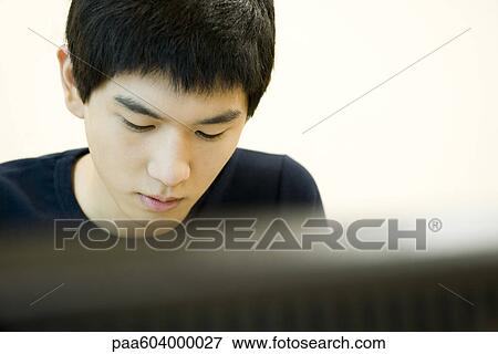 Young man working, looking down in thought View Large Photo Image Stock Photo - Young man working, looking down in thought. Fotosearch