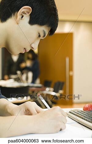 Young man writing at desk View Large Photo Image Stock Image - Young man writing at desk. Fotosearch