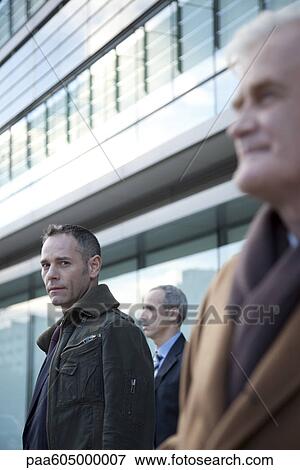 Businessmen standing in front of building View Large Photo Image Stock Photo - Businessmen standing in front of building. Fotosearch