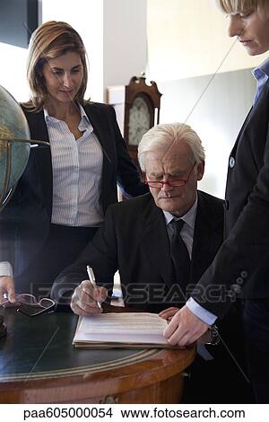 Picture - Executive examining documents, colleagues by his side. Fotosearch