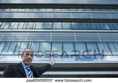 Executive gesturing at office building and smiling View Large Photo Image Stock Photo - Executive gesturing at office building and smiling. Fotosearch