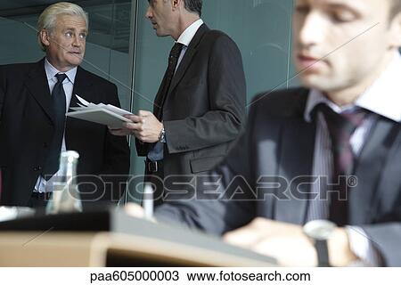 Stock Image - Executive in discussion, young businessman working in foreground. Fotosearch