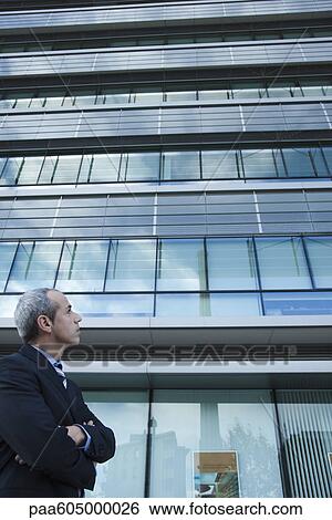 Executive looking at office building in thought View Large Photo Image Stock Photograph - Executive looking at office building in thought. Fotosearch
