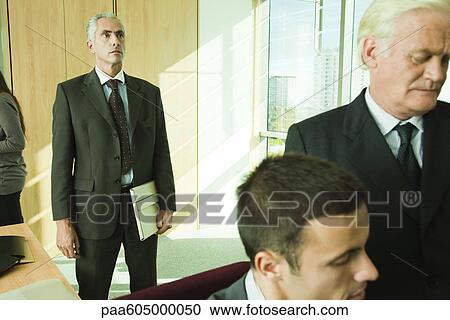 Executive looking into distance in thought, colleagues in foreground View Large Photo Image Stock Image - Executive looking into distance in thought, colleagues in foreground. Fotosearch