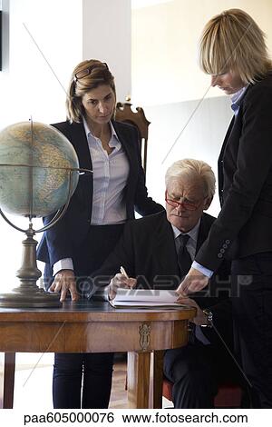 Executive signing paperwork, colleagues by his side View Large Photo Image Stock Photograph - Executive signing paperwork, colleagues by his side. Fotosearch