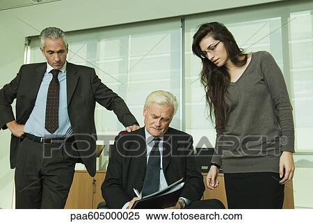 Executive signing paperwork, colleagues standing by his side View Large Photo Image Stock Photography - Executive signing paperwork, colleagues standing by his side. Fotosearch