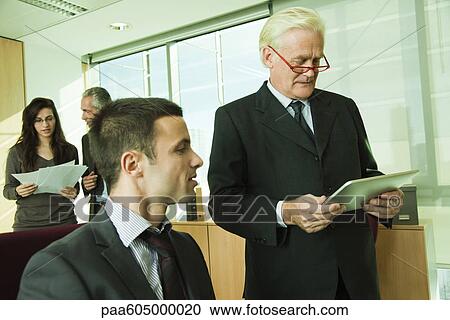 Executive using digital tablet with young associate View Large Photo Image Stock Image - Executive using digital tablet with young associate. Fotosearch