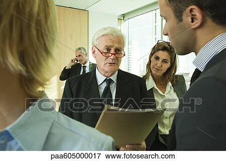 Executives discussing work with young associate View Large Photo Image Stock Photo - Executives discussing work with young associate. Fotosearch