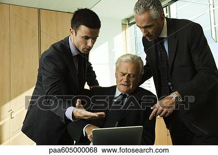 Executives in discussion while looking down at digital tablet View Large Photo Image Stock Photo - Executives in discussion while looking down at digital tablet. Fotosearch