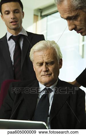 Executives looking down at digital tablet View Large Photo Image Stock Photo - Executives looking down at digital tablet. Fotosearch
