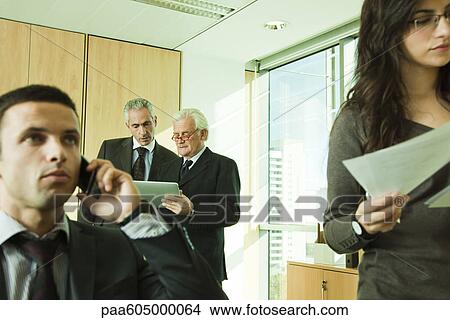 Executives using digital tablet, young associates working in foreground View Large Photo Image Picture - Executives using digital tablet, young associates working in foreground. Fotosearch