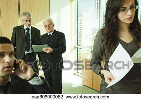 Executives using digital tablet, young associates working in foreground View Large Photo Image Stock Image - Executives using digital tablet, young associates working in foreground. Fotosearch
