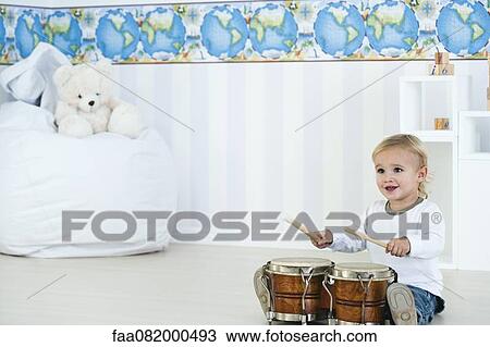 Stock Image - Baby boy playing drums in nursery. Fotosearch
