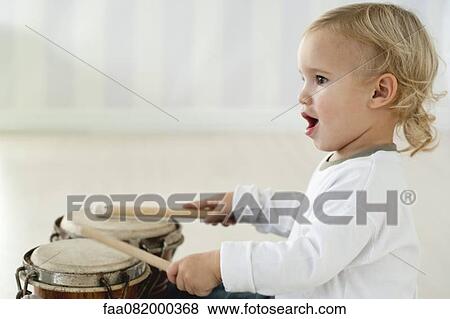 Stock Photo - Baby boy playing drums, side view. Fotosearch