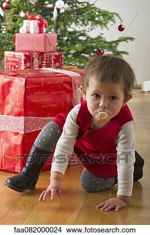 Baby girl crouching in front of Christmas presents View Large Photo Image Picture - Baby girl crouching in front of Christmas presents. Fotosearch