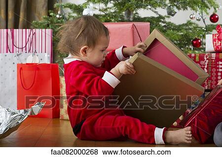 Stock Photo - Baby girl opening Christmas present. Fotosearch