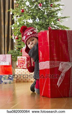 Baby girl peeking at large Christmas present View Large Photo Image Picture - Baby girl peeking at large Christmas present. Fotosearch