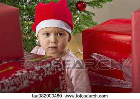 Baby girl sitting by Christmas presents with sulky expression on face View Large Photo Image Stock Image - Baby girl sitting by Christmas presents with sulky expression on face. Fotosearch