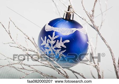 Stock Photo - Blue bauble hanging from silver branches. Fotosearch