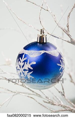 Stock Photography - Blue bauble hanging from silver branches. Fotosearch
