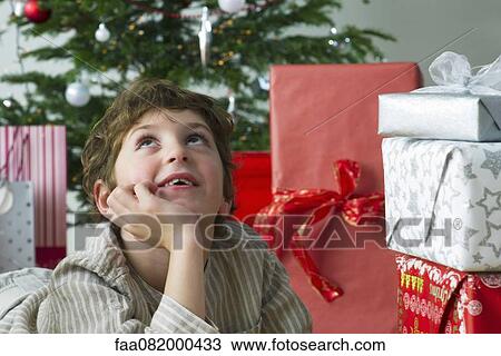 Boy lying beside Christmas presents, daydreaming View Large Photo Image Stock Image - Boy lying beside Christmas presents, daydreaming. Fotosearch