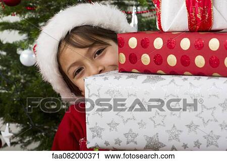 Boy peeking around stack of Christmas presents View Large Photo Image Stock Image - Boy peeking around stack of Christmas presents. Fotosearch