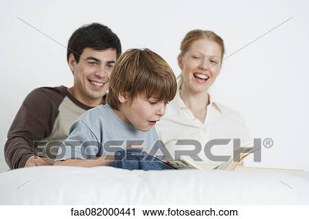 Boy reading book with parents View Large Photo Image Stock Image - Boy reading book with parents. Fotosearch