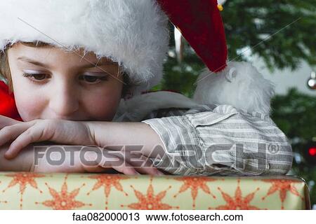Boy resting head on Christmas present View Large Photo Image Stock Image - Boy resting head on Christmas present. Fotosearch