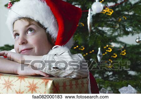 Boy resting head on Christmas present, daydreaming View Large Photo Image Stock Image - Boy resting head on Christmas present, daydreaming. Fotosearch