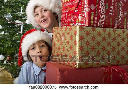 Boys peeking around stack of Christmas presents View Large Photo Image Stock Photography - Boys peeking around stack of Christmas presents. Fotosearch