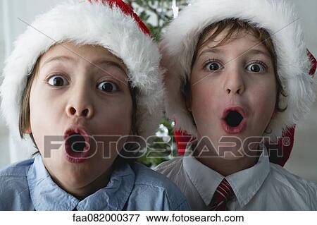 Stock Photo - Boys wearing Santa hats, making surprised faces. Fotosearch