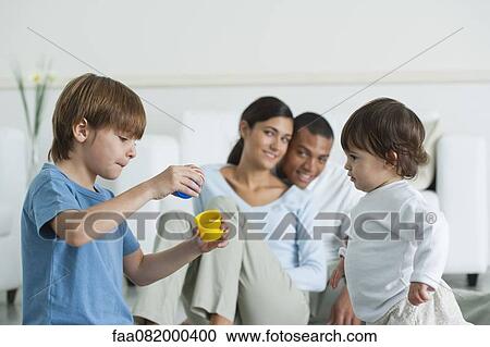 Stock Image - Brother and sister playing, parents in background. Fotosearch