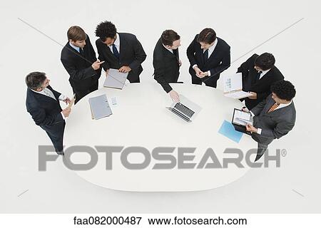 Stock Photo - Business associates working together in pairs around table. Fotosearch