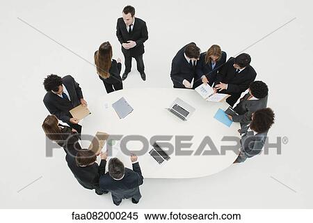 Stock Photography - Business associates working together in groups around table. Fotosearch